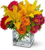 Orange roses and alstroemeria, yellow Asiatic lilies, pink Matsumoto asters, hot pink miniature gerberas and green button spray chrysanthemums – accented with oregonia and solidaster